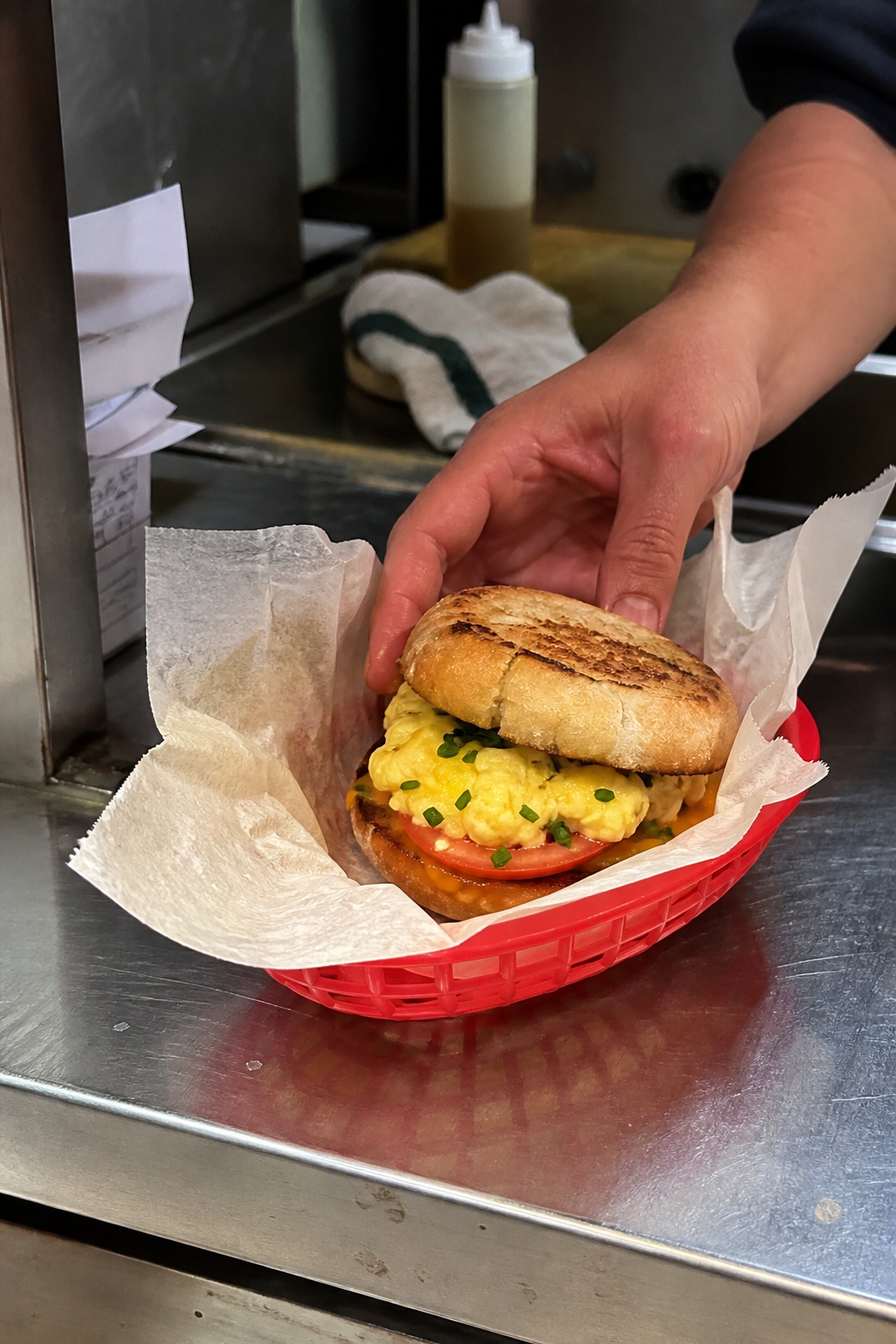 Synthetic service photograph of an egg and tomato sandwich arriving in a paper-lined red basket