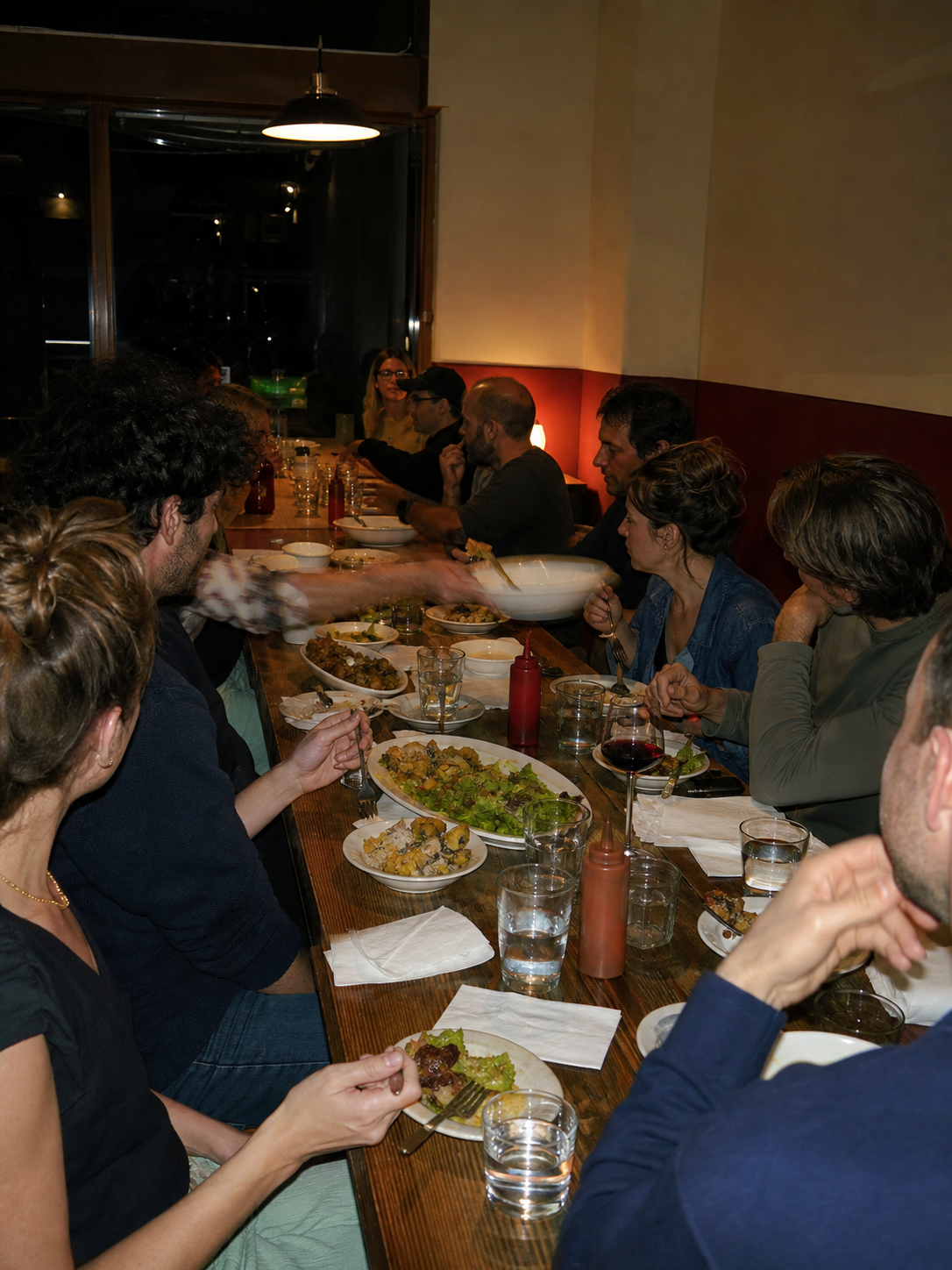 Synthetic direct-flash photograph of a fictional neighborhood supper around one long communal table